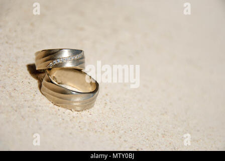 Gli anelli di nozze sulla sabbia al sole Foto Stock
