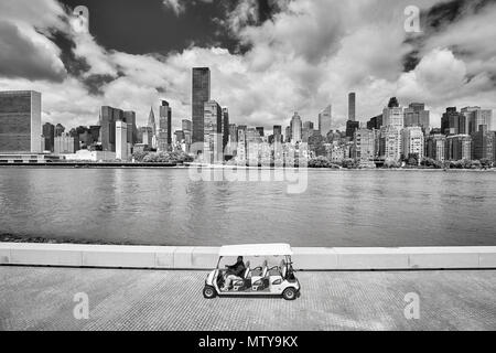 La città di New York, Stati Uniti d'America - 26 Maggio 2017: Passeggeri golf cart sul Franklin D. Roosevelt quattro libertà Park promenade, New York skyline della città in background. Foto Stock