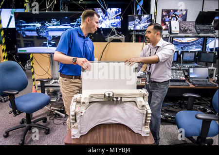 La NASA Extravehicular attività (EVA) trainer, Steve Vilano, mutandine astronauta Col. Tyler "Nick" Aia concernente le caratteristiche operative e di utilizzo dell'aiuto semplificata per EVA Rescue (più sicuro) pack. Aia utilizzato Virtual Reality marcia alla pratica utilizzando il pacco durante un emergenza spacewalk per tornare alla Stazione Spaziale Internazionale in realtà virtuale di laboratorio presso Johnson Space Flight Center a Houston, Tex., apr. 26, 2017. Foto Stock