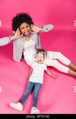 Madre e figlia seduti sul pavimento e urlando in rosa Foto Stock