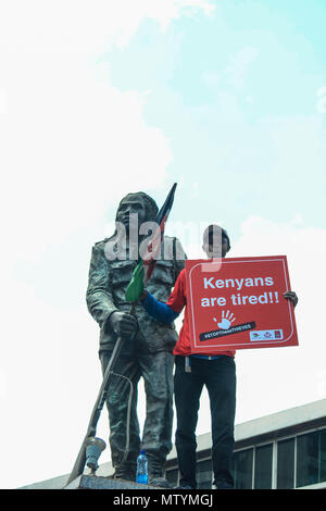 Nairobi, in Kenya. 31 Maggio, 2018. Un protestor targhetta portano in piedi accanto alla statua della libertà fighter Dedan Kimathi come i keniani hanno protestato per le strade. I dimostranti prendere la strada per chiamare il governo ad arrestare le persone coinvolte in un massiccio scandali di corruzione. In un recente scandalo di National Youth Service (NYS), il governo del Kenya ha perso Ksh9 miliardi in dubbie offerte di gara. Credito: SOPA Immagini limitata/Alamy Live News Foto Stock