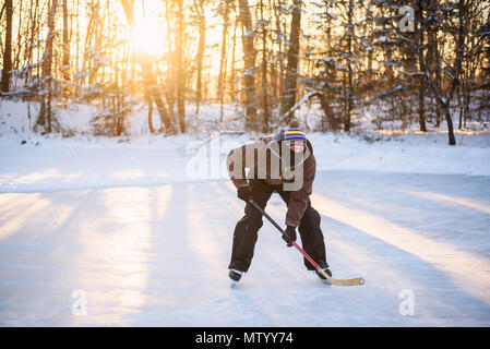 L'uomo la riproduzione di hockey su ghiaccio su un lago ghiacciato Foto Stock