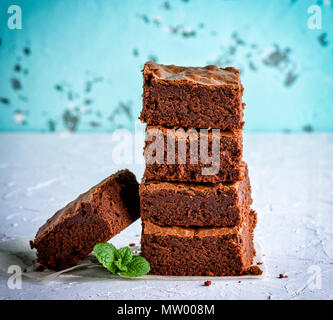 Pila di strati quadrati di cotto torta brownie su una superficie bianca Foto Stock