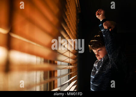 Stanco Ragazzo accanto a una finestra stretching Foto Stock