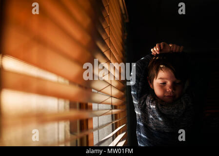 Stanco Ragazzo accanto a una finestra stretching Foto Stock