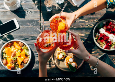 Vista aerea di tre donne che fanno un brindisi celebrativo con aperol spritz cocktail Foto Stock