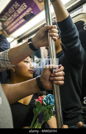 Piloti di condividere un palo per equilibrio, mentre cavalcate un affollato uptown Rush Hour treno della metropolitana nel centro di Manhattan. NYC. Foto Stock