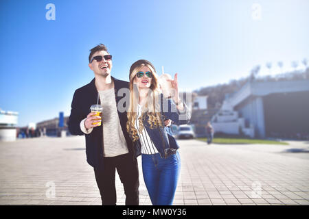 Coppia sorridente a piedi alla strada nel weekend e bere qualche cocktail. Foto Stock