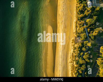 Vista aerea della spiaggia dell'oceano al tramonto - guardando dritto verso il basso in corrispondenza di acqua, sabbia, avvolgimento Boardwalk e tavoli per picnic Foto Stock