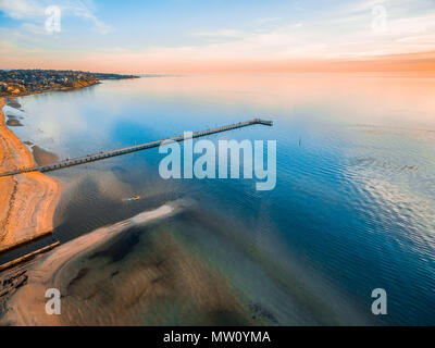 Il molo che si estende nella baia tranquilla acqua al tramonto - vista aerea Foto Stock