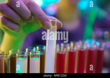 La donna sta cercando un cocktail alcoolico in tubi di prova. Foto Stock