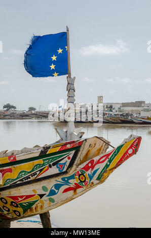 St Louis, Senegal - 12 Ottobre 2014: i colori di legno verniciato la pesca in barca o in piroga con la bandiera dell'Unione europea a costa. Foto Stock