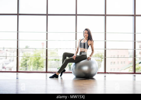 Giovane donna sorridente in sportswear, facendo esercizio di fitness con fit ball, in interni. Uno stile di vita sano, peso lossing e tema sportivo concetto shot. Foto Stock