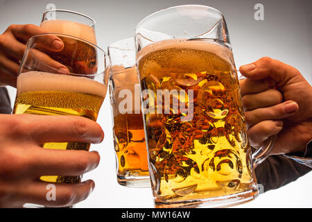 Mani con boccali di birra creazione di tostatura splash isolati su sfondo bianco Foto Stock