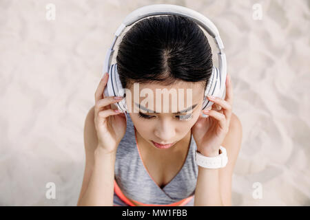 Bella donna asiatica con le cuffie ascoltando musica Foto Stock