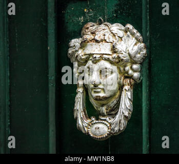 Respingente decorativo realizzato come un uomo di testa su una porta verde. Foto Stock