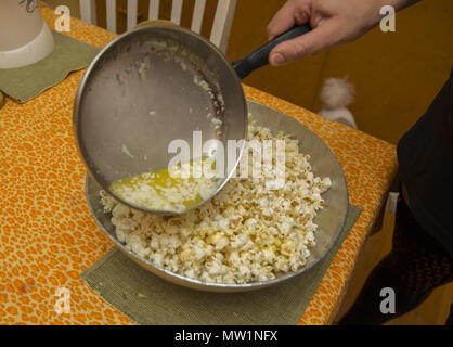 Fare popcorn con un popper elettrico a casa. Mescolare con il burro fuso. Foto Stock