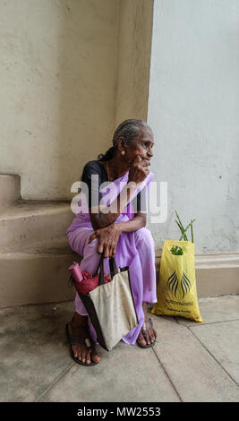 Galle, Sri Lanka - Set 9, 2015. Una vecchia donna seduta e attendere alla strada del mercato di Galle, Sri Lanka. Foto Stock