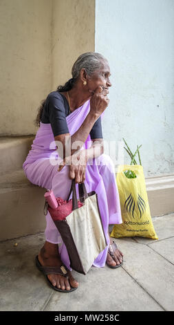 Galle, Sri Lanka - Set 9, 2015. Una vecchia donna seduta e attendere alla strada del mercato di Galle, Sri Lanka. Foto Stock