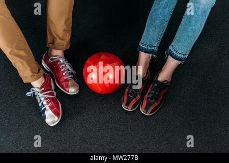 Ritagliato shot del giovane nel noleggio di scarpe da bowling con sfera Foto Stock