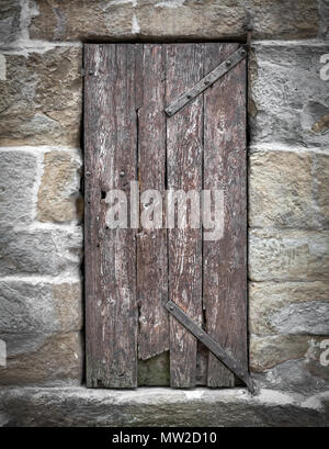 Vecchio di legno porta battente con cerniere di ferro nella casa di pietra. In stile retrò. Foto Stock