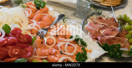 Piatto gourmet di salmone affumicato, pomodori, cipolle, calibri, prosciutto e uva. Foto Stock