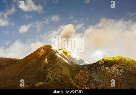 Pennacchi di fumo in aumento dalla vetta del monte Etna, Sicilia, Italia. Colorato paesaggio montano contro il cielo blu sullo sfondo Foto Stock