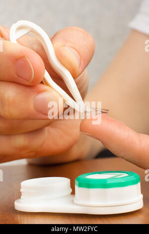 Le mani della donna mettendo su lenti a contatto Foto Stock