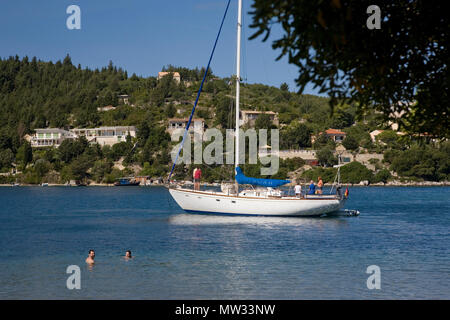 La spiaggia a Moggonissi, sulla punta meridionale di Paxos Grecia: nuotatori e un yacht ancorati Foto Stock