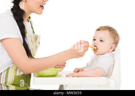 Ritagliato colpo di alimentazione madre piccolo figlio seduto nel seggiolone isolati su sfondo bianco Foto Stock