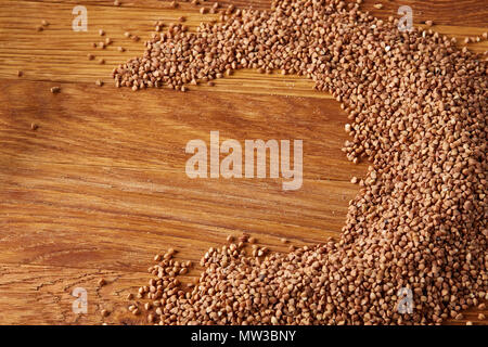 Semole e semolini di grano saraceno disposte a semicerchio su sfondo di legno, vista dall'alto, close-up, il fuoco selettivo. Alcuni di questi testi lo spazio per il tuo testo. Premio per i cereali Foto Stock