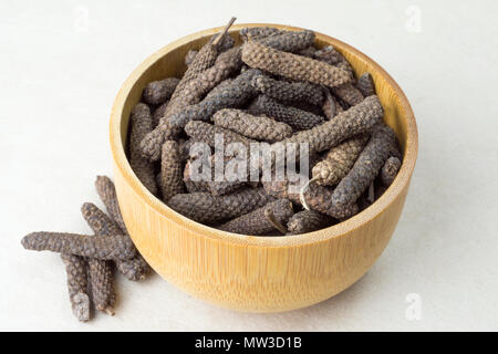 Peperoni interi (Piper longum) in una ciotola di legno Foto Stock