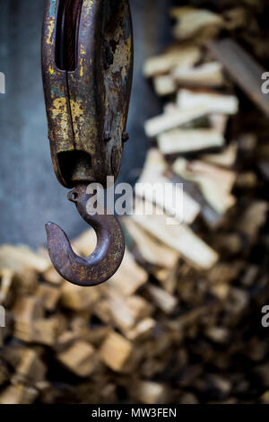 Big rusty gancio di acciaio pesa sullo sfondo delle barre di legno Foto Stock