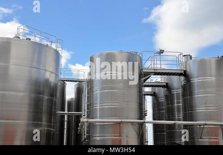 Grandi serbatoi in acciaio per la maturazione del vino, sfondo con cielo nuvoloso, cantina di moderne attrezzature e closeup, vista dal basso Foto Stock