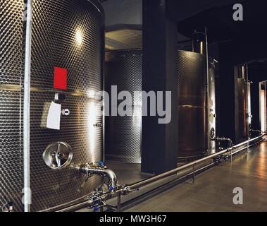 Grandi fermentatori acciaio serbatoi stand in una fila, vino moderno equipaggiamento di fabbrica Foto Stock