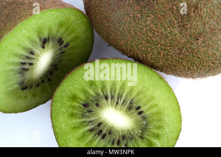 Kiwi verde tagliato a metà accanto a un intero isolato su sfondo bianco Foto Stock