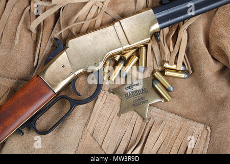 Wild West periodo il fucile a ripetizione con munizioni e sheriff badge Foto Stock