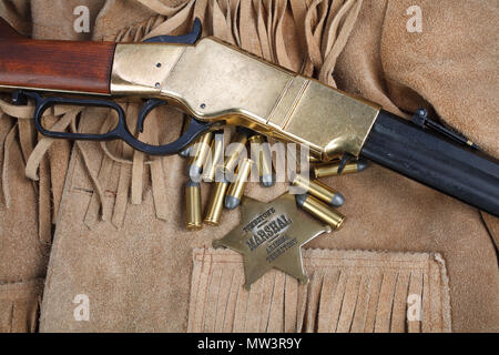 Wild West periodo il fucile a ripetizione con munizioni e sheriff badge Foto Stock