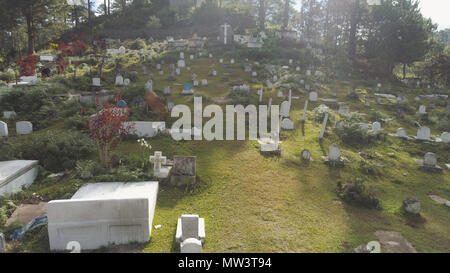 Vista aerea del cimitero cattolico di bianco lapidi, tombe e croci in montagna provincia di Sagada. Mucca pascolare nel cimitero. Filippine, Luzon. Foto Stock