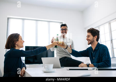 La gente di affari per celebrare il successo da tostare un drink seduti in ufficio. Happy office colleghi seduti nella sala conferenze con i laptop sul tavolo toa Foto Stock