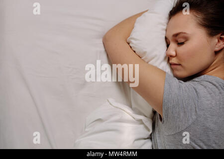 Vista dall'alto di una donna che dorme sul letto tenendo un cuscino. In prossimità di una donna in un sonno profondo. Foto Stock