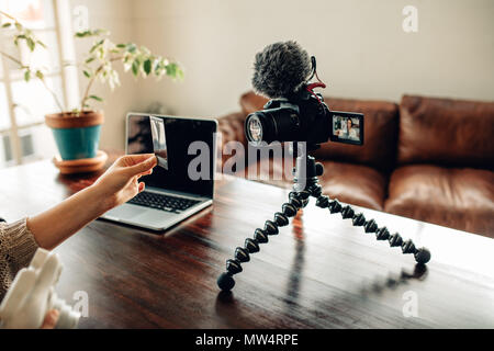 Vista posteriore del blogger che mostra una fotografia scattata con una fotocamera istantanea durante la registrazione video contenuti per il suo blog. Blogger contenuto registrazione per lei Foto Stock