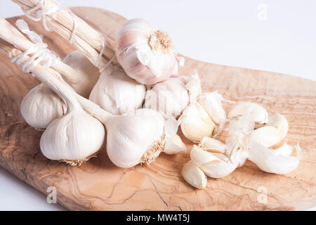 Bulbi di aglio e chiodi di garofano acquistato da un supermercato in Inghilterra UK GB su un legno di ulivo tagliere su sfondo bianco Foto Stock