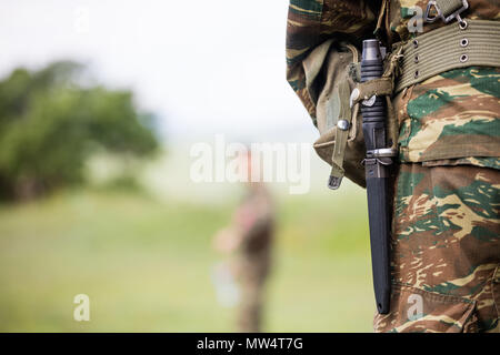 Soldier" corpo che in piedi con Abbigliamento camouflage e coltello nella sua cinghia. Chiudere fino alle spalle di vista, soldato sfocata e natura sfondo, spazio per il testo Foto Stock