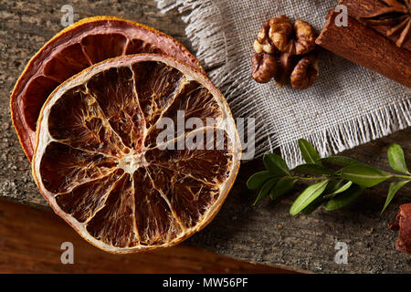 Asciugare fette di arancia frutti, noci e cannella su sfondo di legno, piana, laici close-up, il fuoco selettivo. Studio shot. Vista da sopra. Natale d Foto Stock
