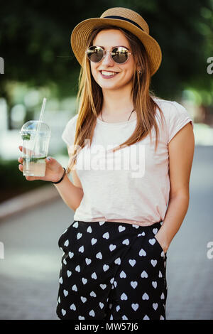 Malinconici donna felice sorseggiando un mojito in strada all'aperto Foto Stock