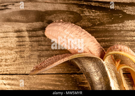 Oro banana pelata su sfondo di legno Foto Stock