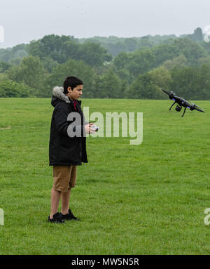 Biracial boy vola drone a Weald Country Park modello di rilascio trattenuto Foto Stock