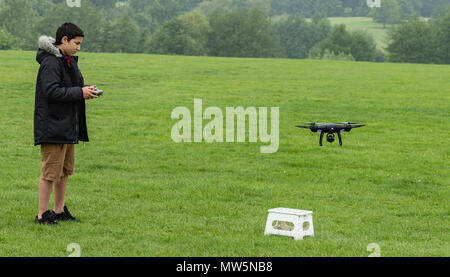 Biracial boy vola drone a Weald Country Park modello di rilascio trattenuto Foto Stock