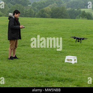 Biracial boy vola drone a Weald Country Park modello di rilascio trattenuto Foto Stock